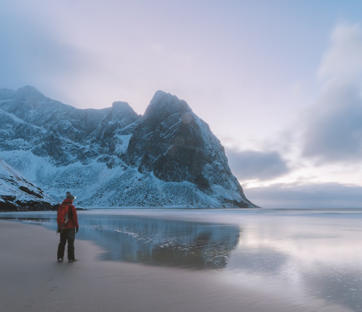 Man on a beach surrounded by mountains; Shutterstock ID 1099591193; your: Alex Butler; gl: 65050; netsuite: Lonely Planet; full: Beaches that are best in winter